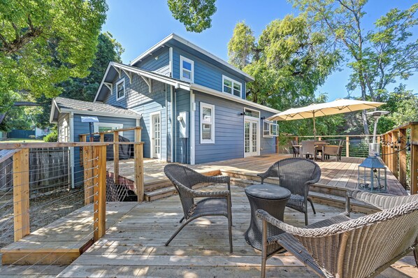 A two-story house with a deck, outdoor furniture, and a covered patio area.