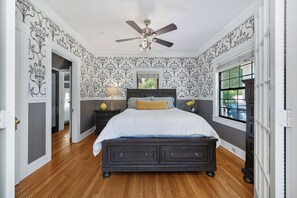 A bedroom with a bed, a ceiling fan, a nightstand, and a window.