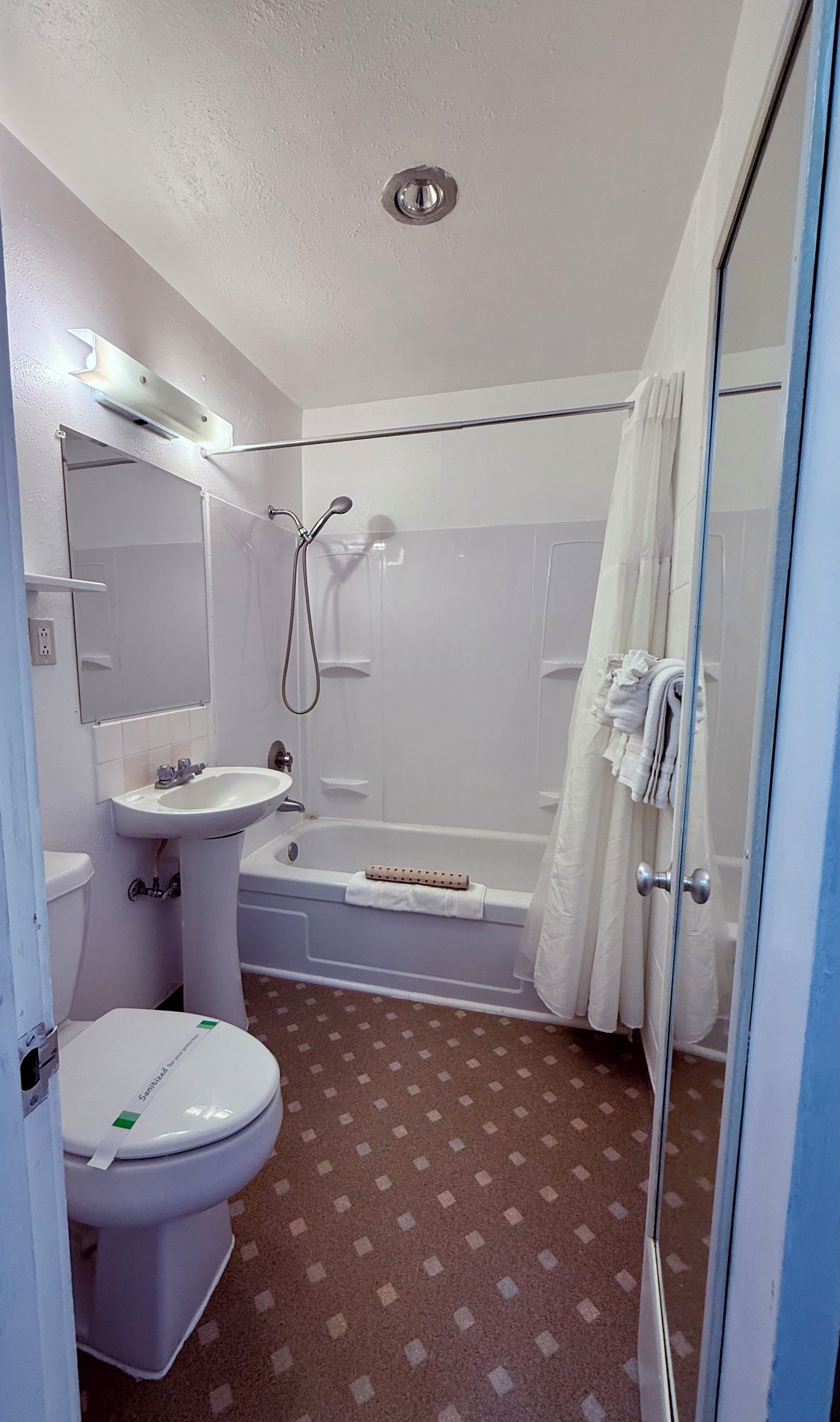 A bathroom with a toilet, sink, bathtub, and shower curtain.