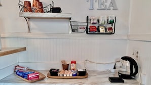 A kitchen counter with tea-related items, a coffee maker, and a shelf with tea bags. - The John Day Motel (John Day)