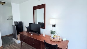 A compact room with a wooden desk, a television, a microwave, and a small refrigerator. - The John Day Motel (John Day)