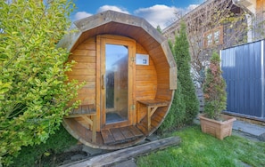 A wooden cabin with a circular door, a small porch, and a wooden bench.