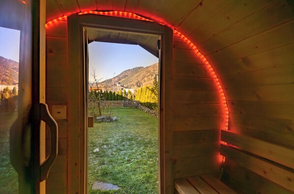 A wooden cabin with a door leading to a grassy yard and a mountain view.