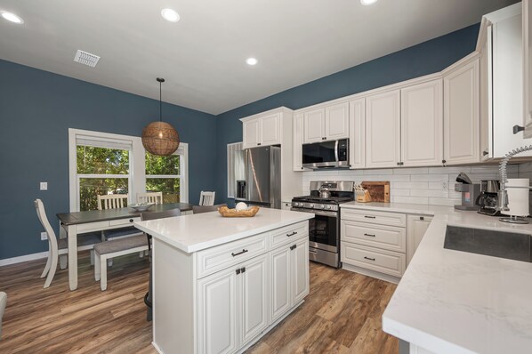 A kitchen with white cabinetry, a central island, and a dining area with a table and chairs.