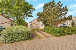 A residential area with brick houses, paved walkways, and green hedges. - Villa in Julianadorp Near Sandy Beach (Julianadorp)