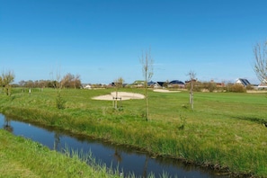 Un parcours de golf doté d’un étang, de bunkers de sable et de quelques arbres clairsemés.