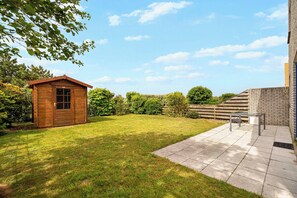 Un abri en bois, une terrasse avec une table et des chaises, et un mur en briques.