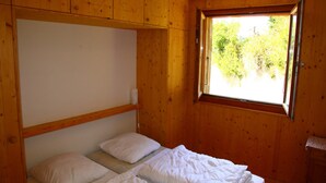 A wooden cabin room with two beds, a window, and a wooden ceiling. - Apartment in Valais Near Cable Car (Nendaz)