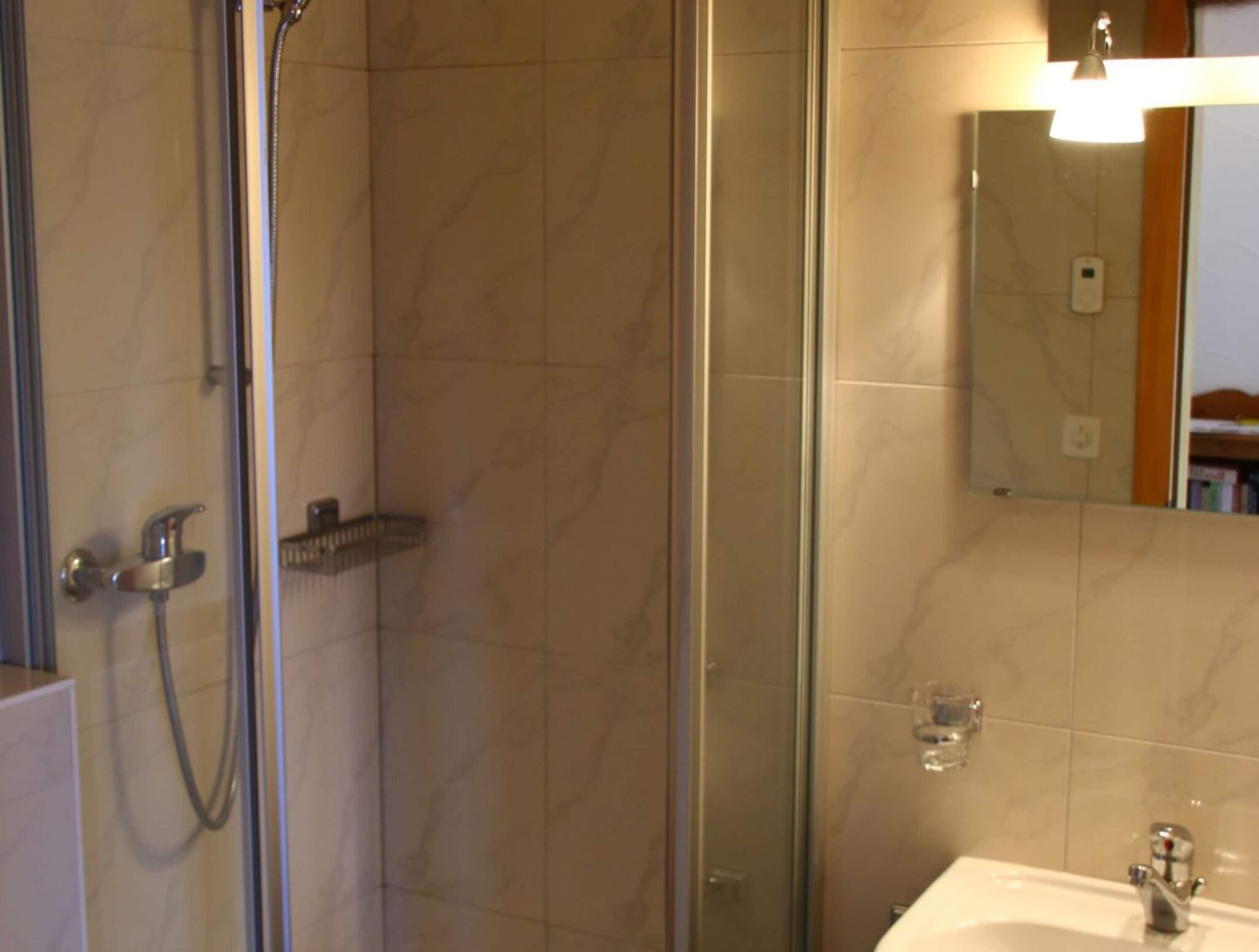 Une salle de bain avec une douche à parois de verre, un lavabo et un miroir.