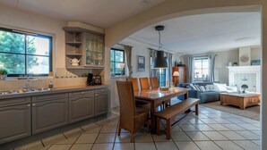 A spacious kitchen with a dining area, large windows, and a fireplace. - Dutch Beach Hideaway w/ Parking (Callantsoog)