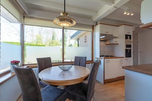 A modern kitchen with white cabinets, a wooden countertop, and a hanging light fixture. - Wildrijk 152 Holiday Home in Sint Maartenszee (Sint Maartensvlotbrug)