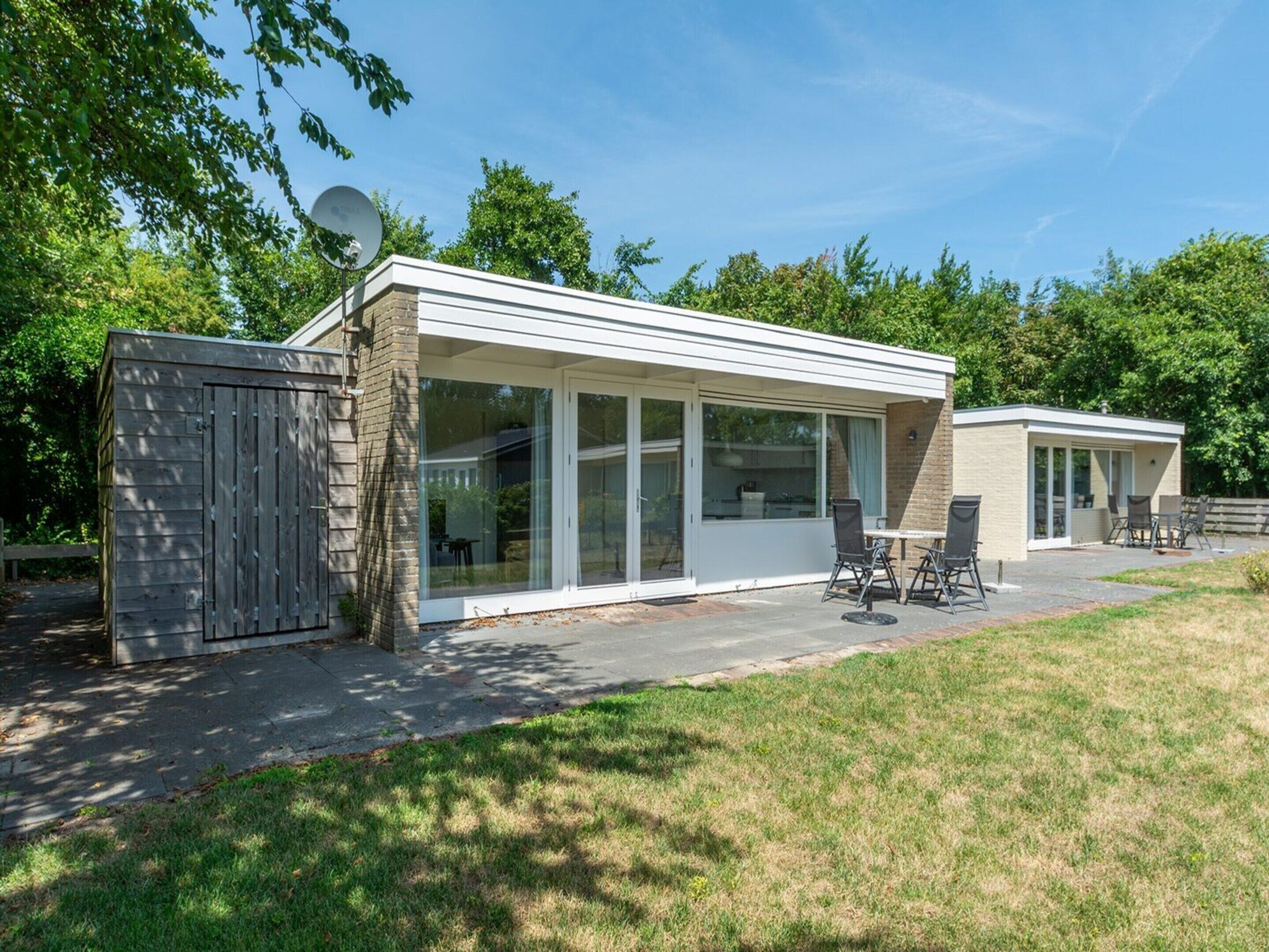 Une maison moderne dotée d’un patio, de grandes portes-fenêtres coulissantes et d’une antenne parabolique.
