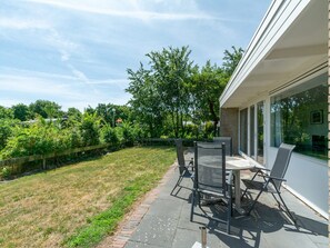A patio with outdoor furniture, a brick pathway, and a view of a green lawn and trees. - Bungalow in Callantsoog Near Sandy Beaches (Callantsoog)