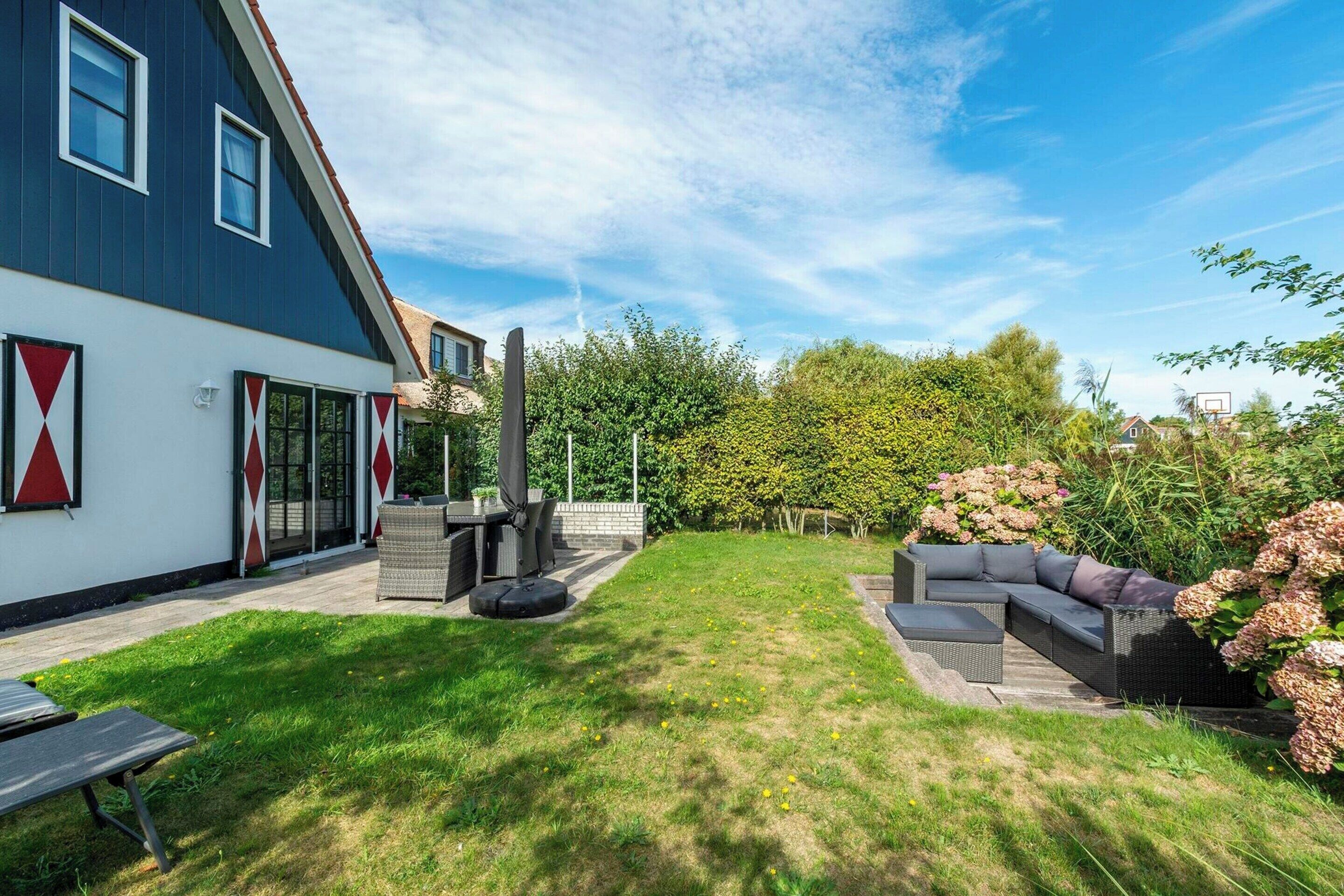Una propiedad residencial con un patio trasero grande, mobiliario exterior y un diseño de casa moderno.