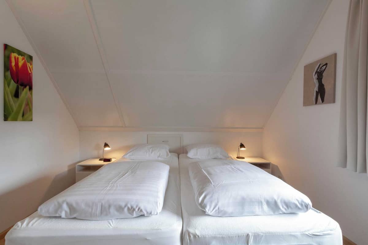 A twin room with two single beds, bedside tables, lamps, and wall art.