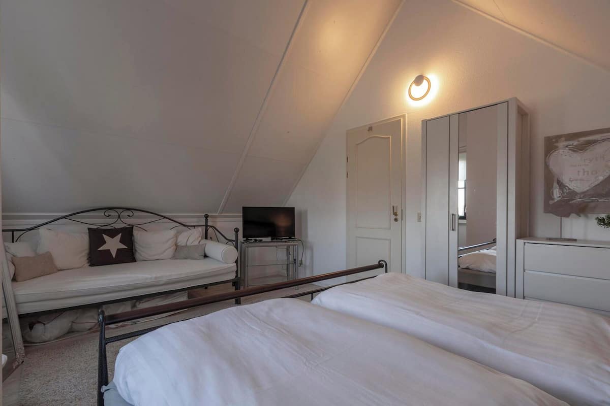 A bedroom with two beds, a television, a wardrobe, and a ceiling light.