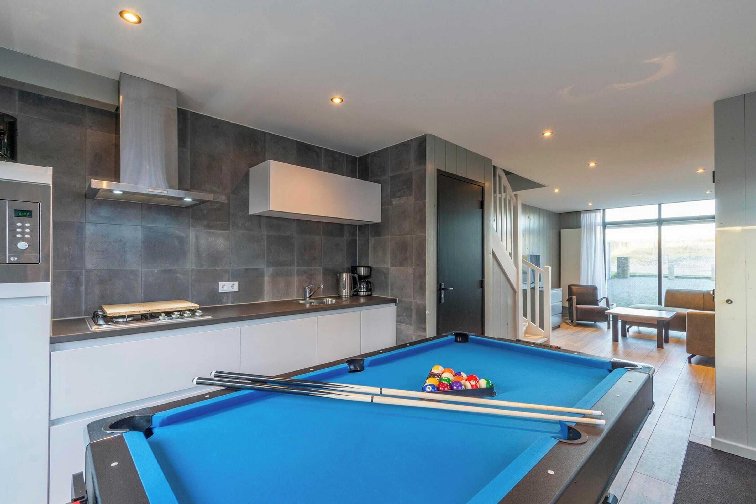Une cuisine moderne équipée d’une table de billard intégrée, d’une cuisinière et d’un four à micro-ondes.