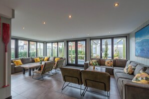 Una habitación amplia con un gran ventanal, un sofá, una mesa y sillas.