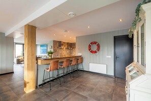 A modern kitchen with a central island, bar stools, and a decorative wreath on the wall. - Callantsoog Group Getaway Beach (Callantsoog)