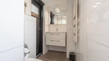 Une petite salle de bain comprenant des toilettes, un lavabo avec un miroir et une poubelle.