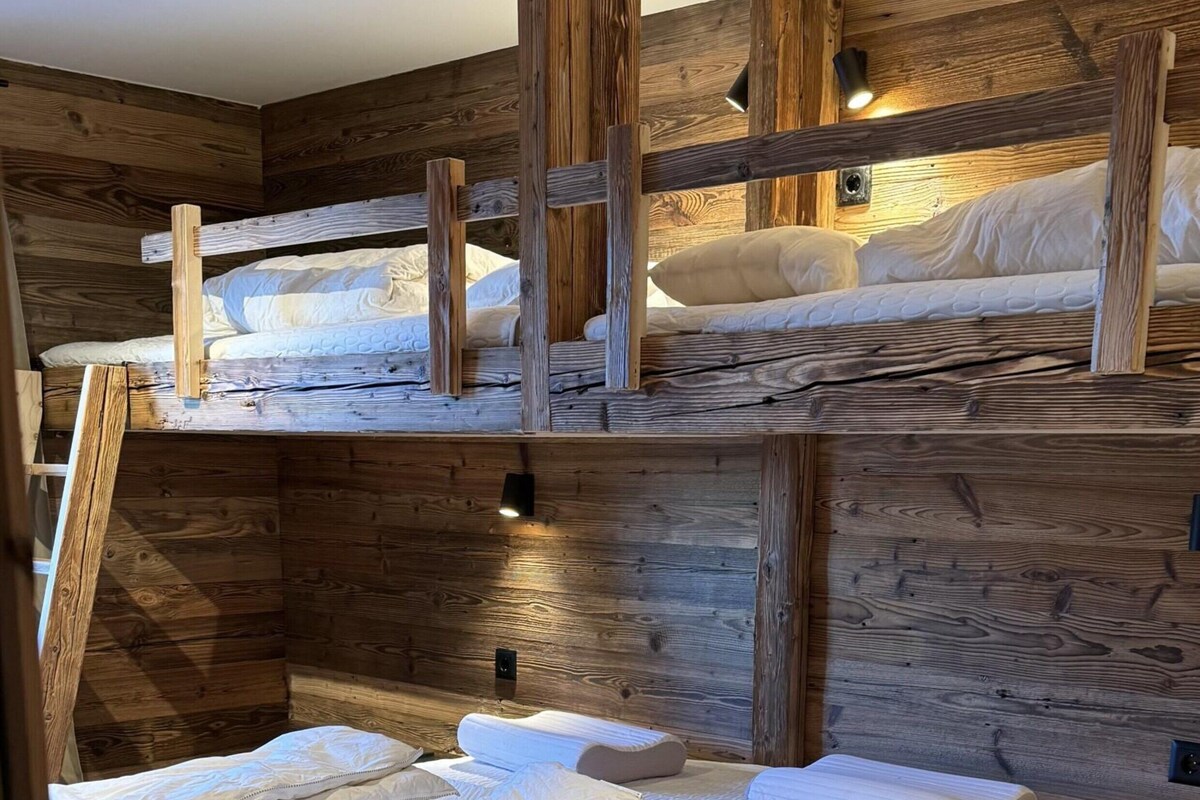 Ein Schlafzimmer mit Etagenbetten, Holzwänden, einem weißen, flauschigen Teppich und einer Nachttischlampe.