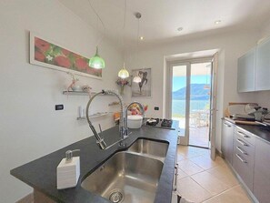 Eine moderne Küche mit einem großen Spülbecken, ein Essbereich mit Blick und ein Balkon mit schöner Aussicht.