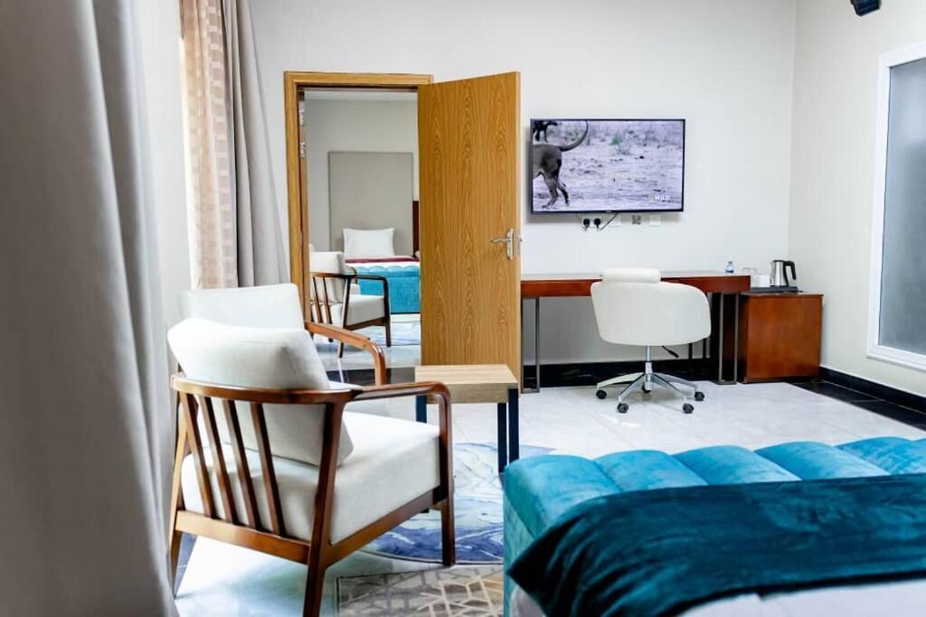 A hotel room with a bed, a desk, a chair, a television, and a door.
