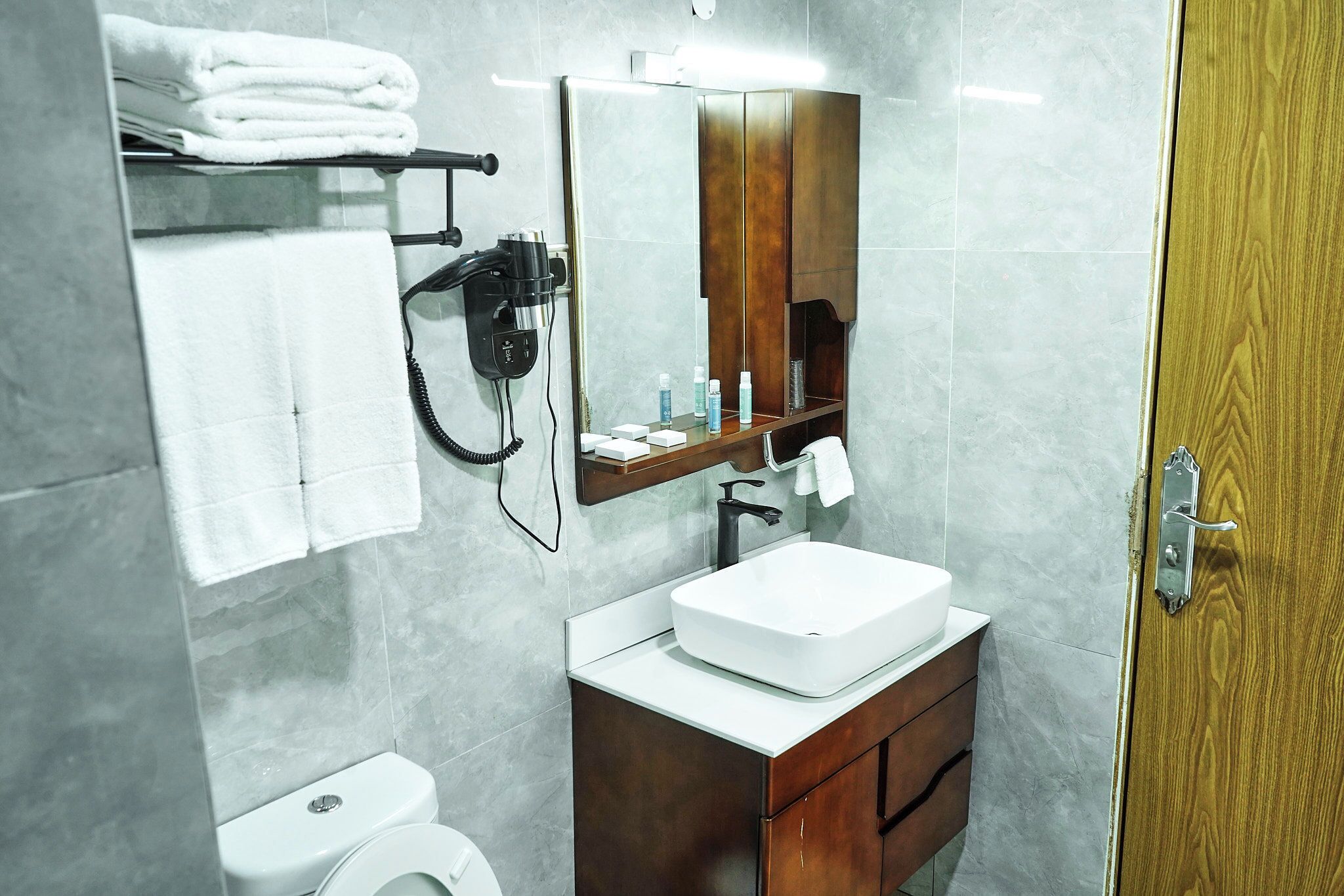 A bathroom with a white sink, a mirror, a towel rack, and a hairdryer.