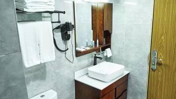 A bathroom with a white sink, a mirror, a towel rack, and a hairdryer.