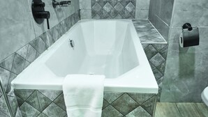 Ein modernes Badezimmer mit freistehender Badewanne, einem Handtuch, einer Toilette und einem Papierhandtuchspender.