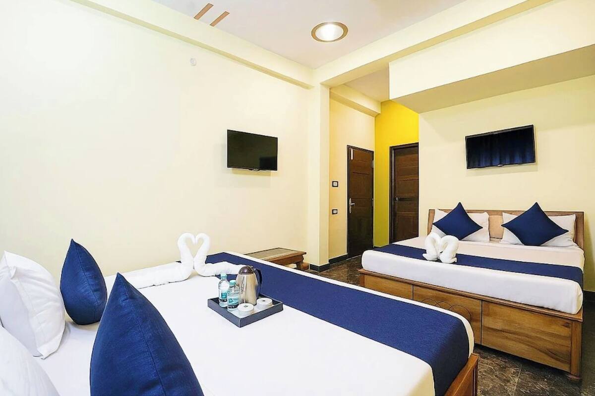 Habitación de hotel con dos camas, un televisor y una puerta que da a otra habitación.