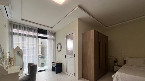 A bedroom with a bed, a desk, a chair, a wardrobe, and a door with a mirror. - EDS Hébergement meublé (Abidjan)
