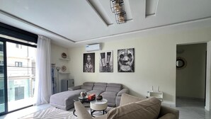 A modern living room with a grey sofa, a patterned rug, and artwork on the wall. - EDS Hébergement meublé (Abidjan)