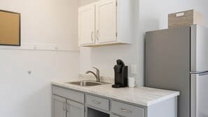 Una cocina moderna con gabinetes blancos, un refrigerador de acero inoxidable y una cafetera integrada.