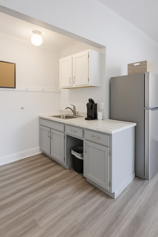 A modern kitchen with white cabinets, a stainless steel refrigerator, and a built-in coffee maker. - Beautiful Studio apartment with AC, Riverside in delightful Bay City! (Bay City)