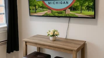 A framed welcome sign for Bay City, Michigan, mounted on a wall above a wooden table with two leather stools.