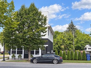 A modern building with a black and white facade, a parked car, and a clear blue sky. - Beautiful Studio apartment with AC, Riverside in delightful Bay City! (Bay City)