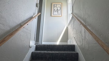 A staircase with a handrail, carpeted steps, and a framed 'HOME' sign on the wall.