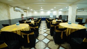A conference room with round tables, black chairs, and yellow sashes. - Hotel V Platina  (Bhubaneshwar)