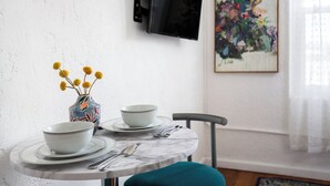 A dining table with bowls, a vase with yellow flowers, a flat-screen TV, and a framed painting on the wall. - Cozy studio in beautiful Los Angeles with air conditioning (Los Angeles)