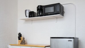 A kitchen with a stainless steel refrigerator, a microwave, and a coffee maker on a shelf. There is a white cabinet with drawers and a wooden countertop. - Cozy studio in beautiful Los Angeles with air conditioning (Los Angeles)