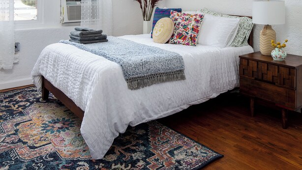 A bedroom with a bed, a nightstand, a lamp, a window with curtains, and two framed pictures on the wall. - Cozy studio in beautiful Los Angeles with air conditioning (Los Angeles)