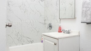 A bathroom with a bathtub, a sink, a mirror, and a shower head. - Cozy studio in beautiful Los Angeles with air conditioning (Los Angeles)