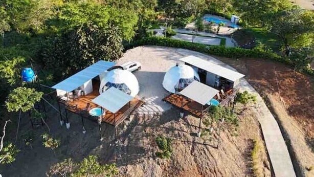 A dome-shaped building with a flat roof, surrounded by trees and a clear sky. - Dome 1 Potrero Beach | Natural Getaway with Ocean View and Private Jacuzzi (Potrero)