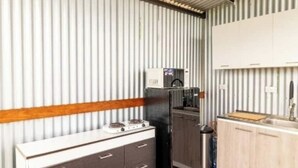 A compact kitchen with a gas stove, a refrigerator, and wooden cabinets. - Dome 1 Potrero Beach | Natural Getaway with Ocean View and Private Jacuzzi (Potrero)