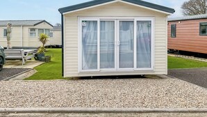Uma casa móvel pequena, de um único quarto, com exterior branco e teto escuro.