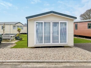 Une petite maison mobile composée d’une seule pièce, avec une façade blanche et un toit foncé.
