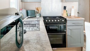 Cozinha moderna com lava-louças embutida, fogão e micro-ondas.
