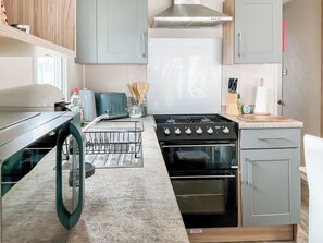 Une cuisine moderne équipée d’un lave-vaisselle encastré, d’une cuisinière et d’un four à micro-ondes.