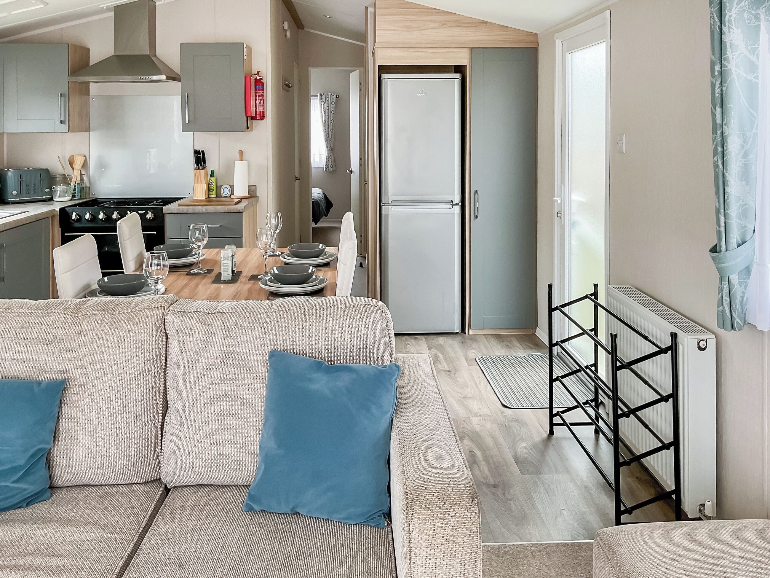 A compact living space with a kitchenette, dining area, and a sofa with cushions.